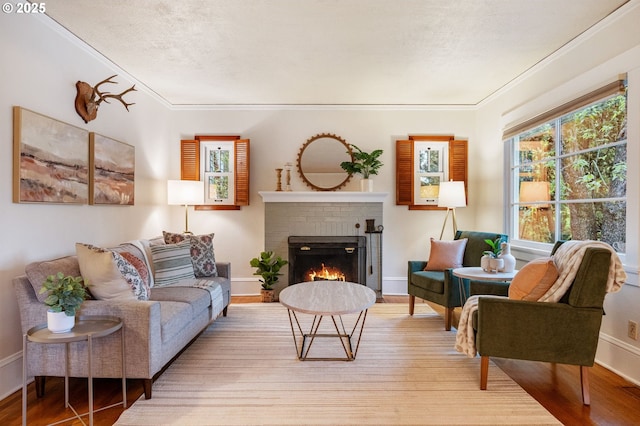 living area featuring crown molding, baseboards, a brick fireplace, and wood finished floors