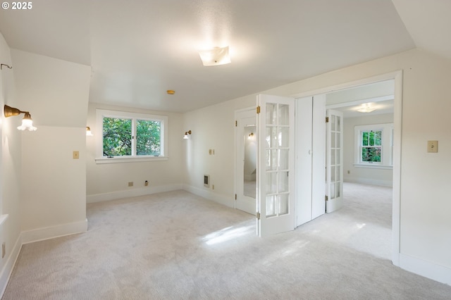 spare room with carpet floors, baseboards, a wealth of natural light, and french doors