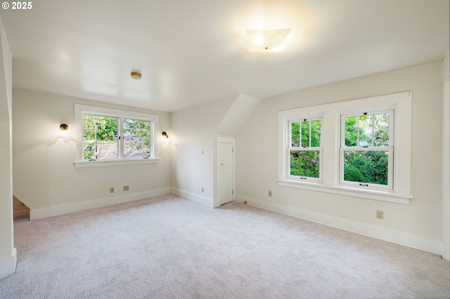 additional living space with a healthy amount of sunlight, baseboards, and light colored carpet