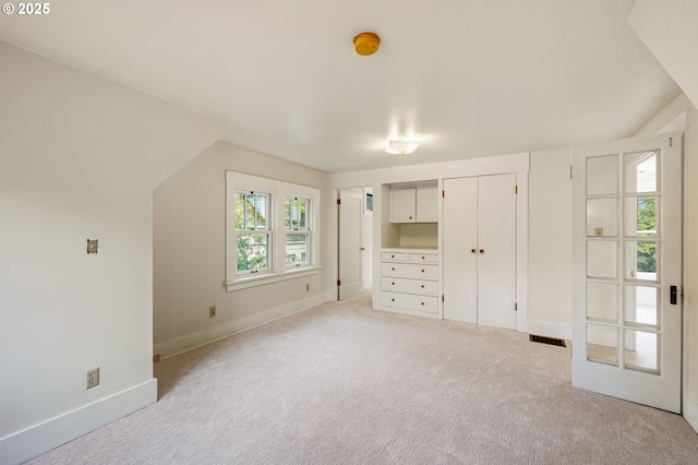 unfurnished bedroom with visible vents, baseboards, multiple closets, and light colored carpet
