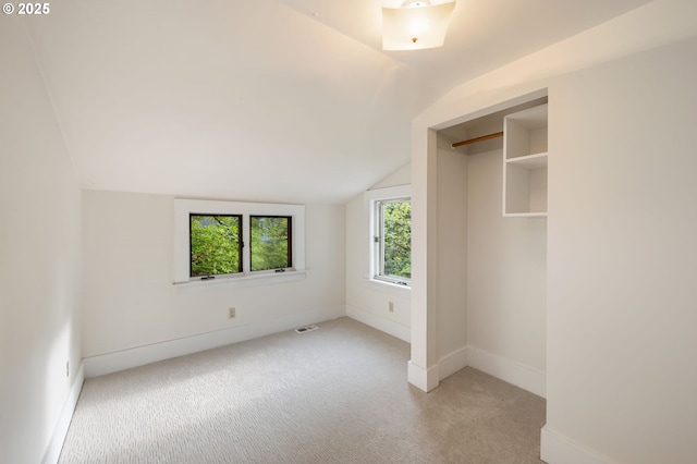 unfurnished bedroom with baseboards, visible vents, carpet, and lofted ceiling