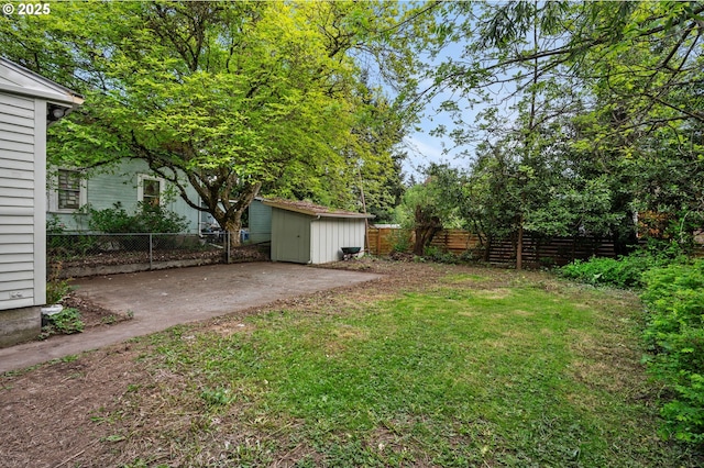 view of yard with a fenced backyard, an outbuilding, a shed, and a patio
