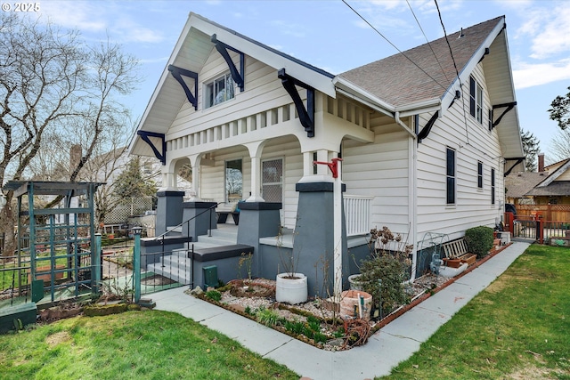 view of front of house with a porch, a shingled roof, fence, a gate, and a front yard