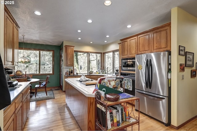 kitchen with appliances with stainless steel finishes, an inviting chandelier, hanging light fixtures, light hardwood / wood-style floors, and a textured ceiling