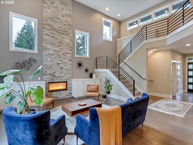 living room with baseboards, a high ceiling, a fireplace, stairway, and wood finished floors