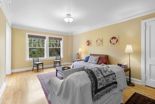 bedroom with wood finished floors, baseboards, and ornamental molding