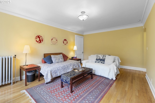 bedroom featuring baseboards, ornamental molding, radiator, and wood finished floors
