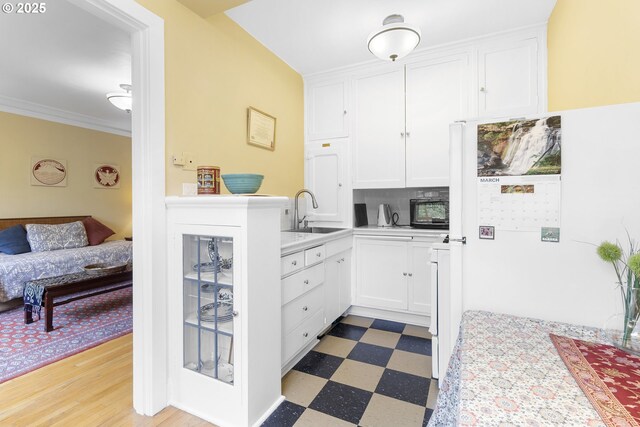 kitchen with light countertops, a sink, white cabinetry, and light floors