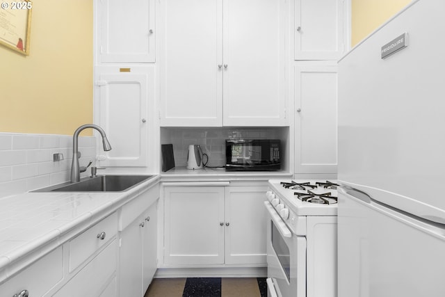 kitchen featuring white appliances, white cabinetry, backsplash, tile countertops, and a sink