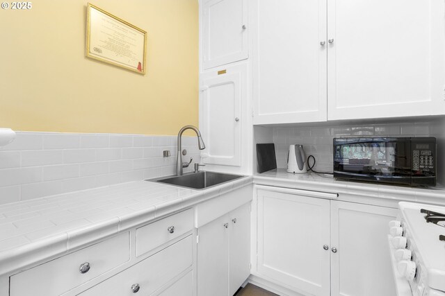 kitchen with tasteful backsplash, black microwave, a sink, and range with gas cooktop