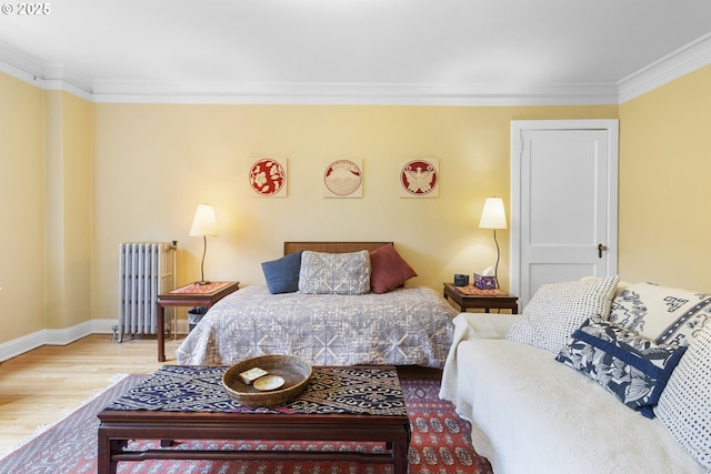bedroom with ornamental molding, baseboards, radiator, and wood finished floors