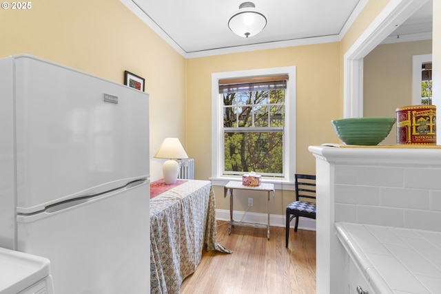 interior space featuring multiple windows, freestanding refrigerator, and crown molding