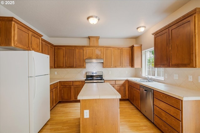 1988 NE 54th Way, Hillsboro, OR 97124 - kitchen with stainless steel appliances, under cabinet range hood, a sink, light wood-style flooring, and a center island