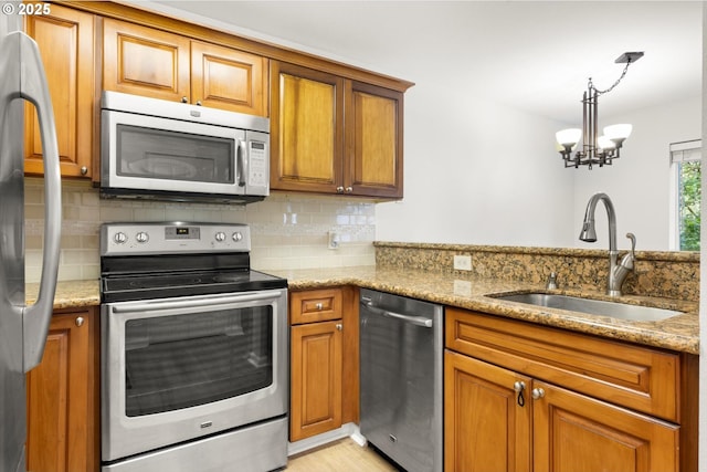 5130 SW Multnomah Blvd Unit H, Portland, OR 97219 - kitchen with stainless steel appliances, brown cabinetry, and light stone counters