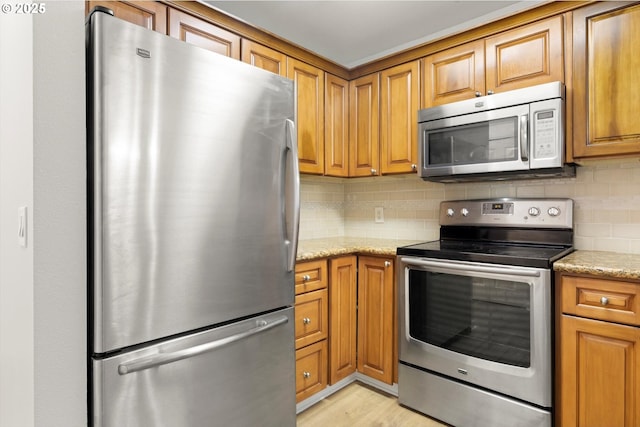 5130 SW Multnomah Blvd Unit H, Portland, OR 97219 - kitchen featuring stainless steel appliances, brown cabinets, backsplash, and light stone countertops