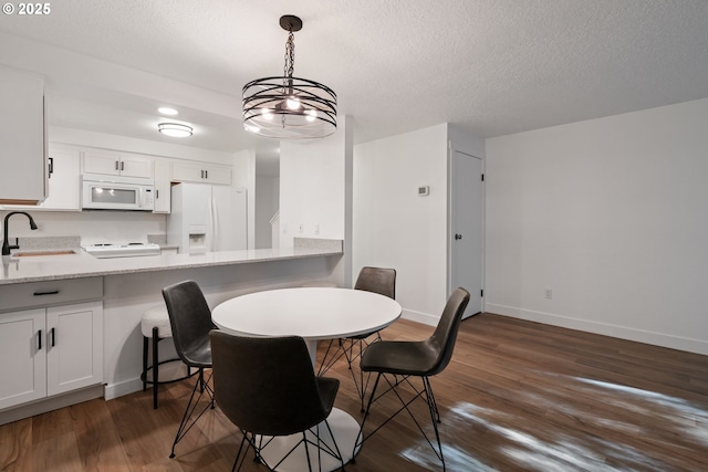 dining area featuring dark wood-style flooring, a textured ceiling, and baseboards