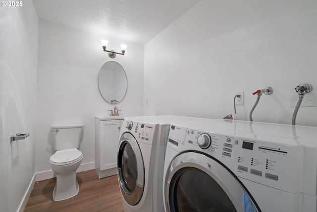 laundry room with laundry area, a textured ceiling, washing machine and clothes dryer, baseboards, and light wood finished floors