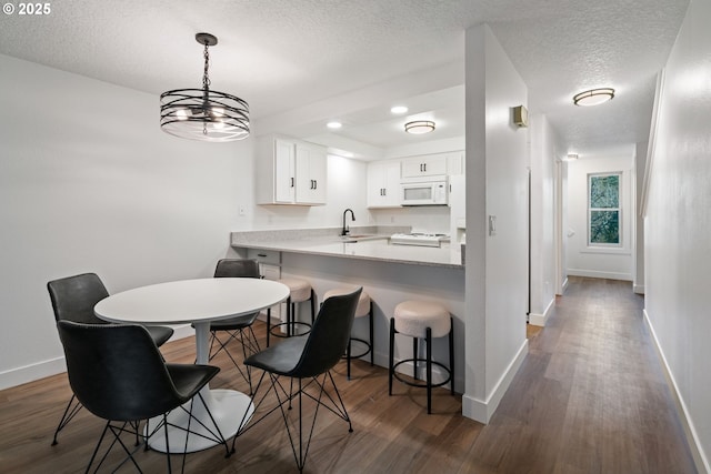 dining room featuring a textured ceiling, baseboards, and dark wood-style floors
