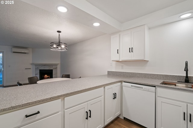 kitchen with a sink, recessed lighting, white cabinetry, white dishwasher, and a premium fireplace