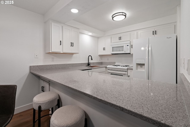 kitchen with a sink, white cabinetry, dark wood-style flooring, baseboards, and white appliances