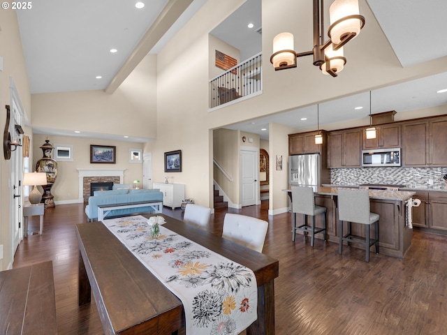 dining room featuring a chandelier, dark wood-style flooring, a fireplace, and baseboards