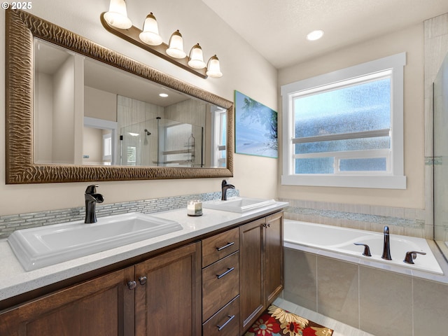 full bathroom with a garden tub, double vanity, a stall shower, and a sink