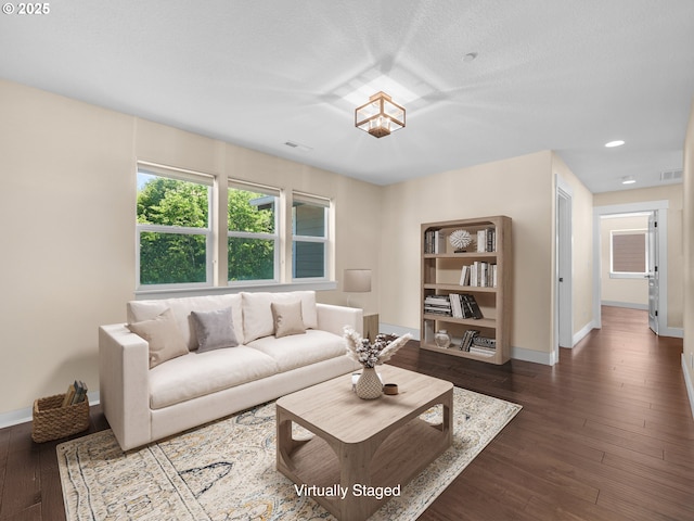 living area featuring dark wood-style flooring, visible vents, and baseboards