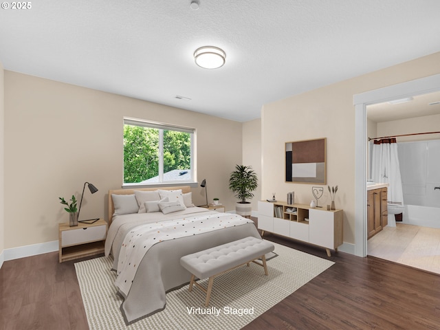 bedroom featuring visible vents, baseboards, connected bathroom, wood finished floors, and a textured ceiling