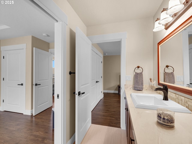 bathroom with wood finished floors, vanity, and baseboards