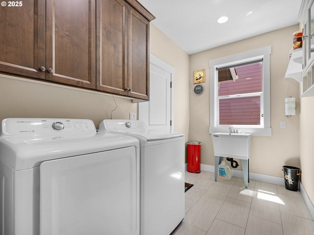 laundry room featuring washing machine and dryer, cabinet space, and baseboards