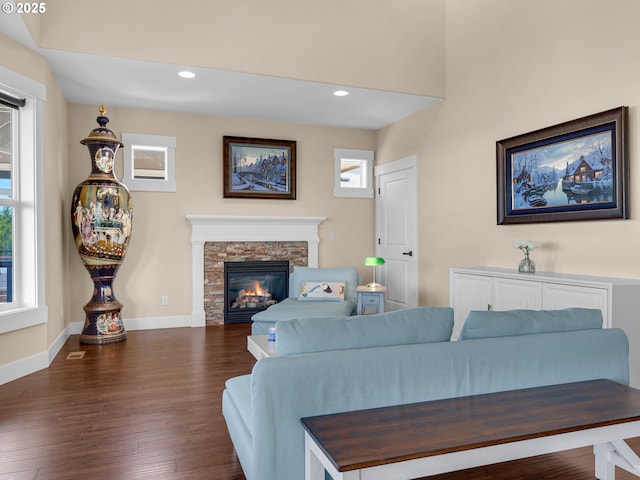 living area with a stone fireplace, recessed lighting, dark wood finished floors, and baseboards