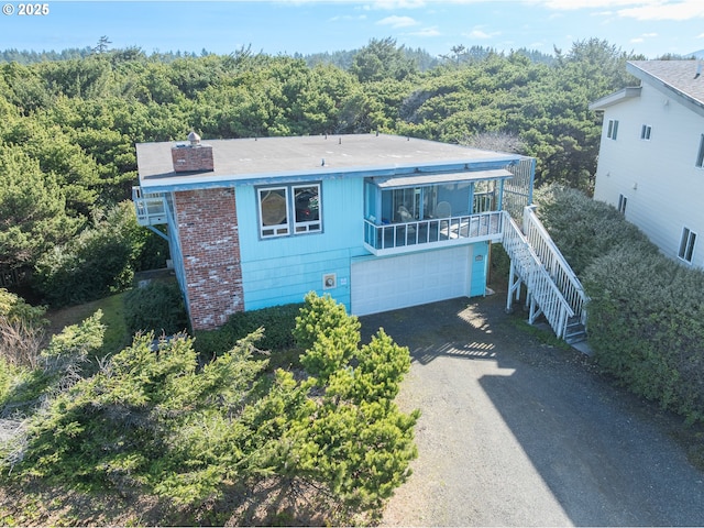 view of front of house with a wooded view, driveway, and stairs