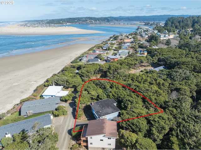 drone / aerial view featuring a beach view, a forest view, and a water view