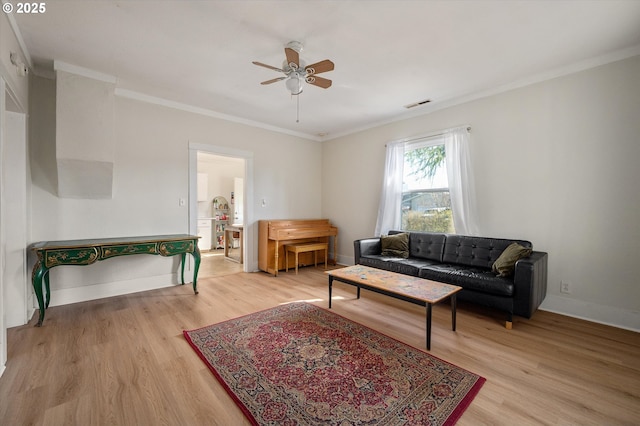 living area with baseboards, visible vents, a ceiling fan, ornamental molding, and light wood-type flooring