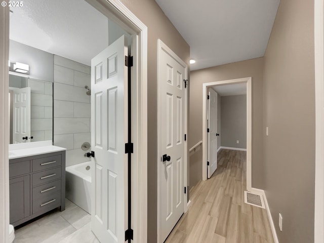 bathroom featuring baseboards, visible vents, wood finished floors, bathtub / shower combination, and vanity