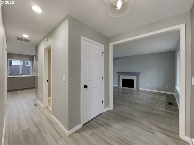 hall with light wood finished floors, baseboards, and visible vents