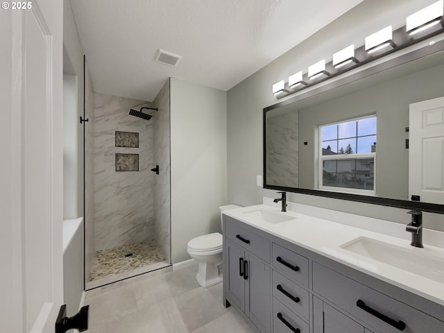 full bathroom featuring visible vents, a sink, a tile shower, and toilet