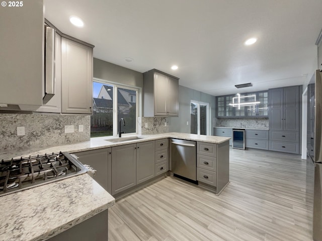 kitchen featuring stainless steel appliances, wine cooler, a sink, and gray cabinetry