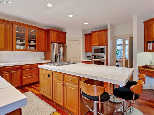 kitchen featuring a kitchen island, light hardwood / wood-style floors, stainless steel appliances, and tasteful backsplash