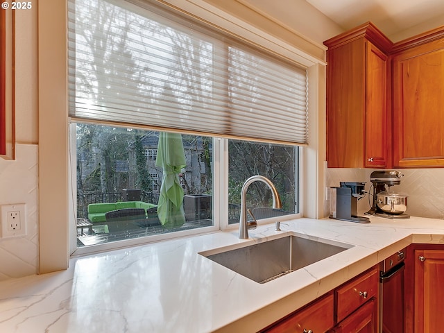 kitchen with decorative backsplash, sink, and light stone countertops