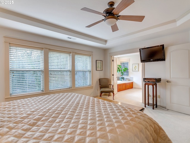 unfurnished bedroom featuring a raised ceiling, connected bathroom, light carpet, and ceiling fan