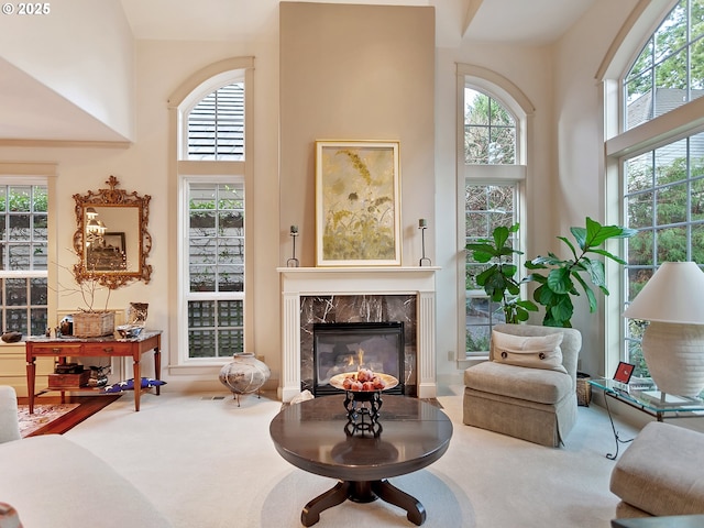 living area featuring carpet floors, a high ceiling, and a high end fireplace