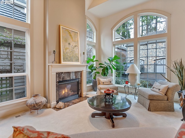 sitting room featuring a wealth of natural light, a fireplace, carpet, and a high ceiling