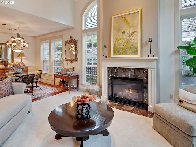 living room with a premium fireplace, a chandelier, and ornamental molding