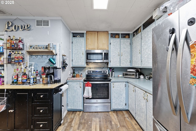kitchen featuring stainless steel appliances, light wood-style flooring, light countertops, and dark cabinetry