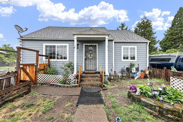 view of front facade featuring fence, roof with shingles, and a gate