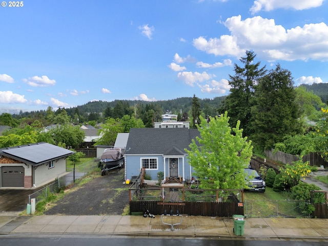 view of front of home featuring a fenced front yard and a forest view