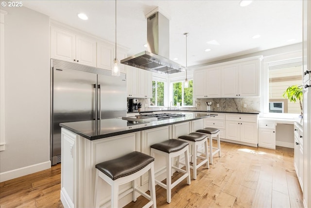 kitchen with backsplash, stainless steel appliances, white cabinetry, and island range hood