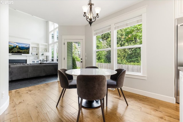 dining area featuring baseboards, a notable chandelier, and light wood-type flooring