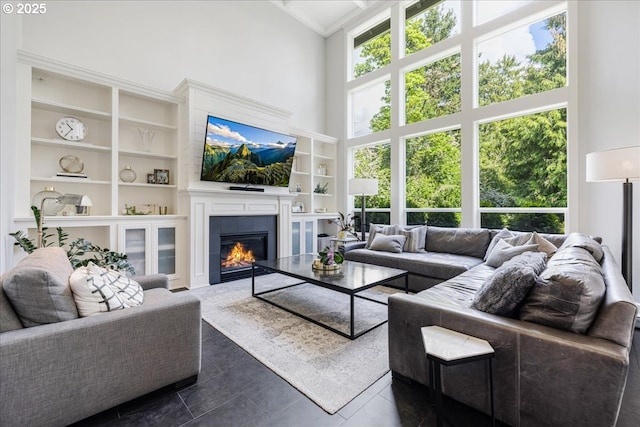 living room featuring built in features, a high ceiling, and a fireplace